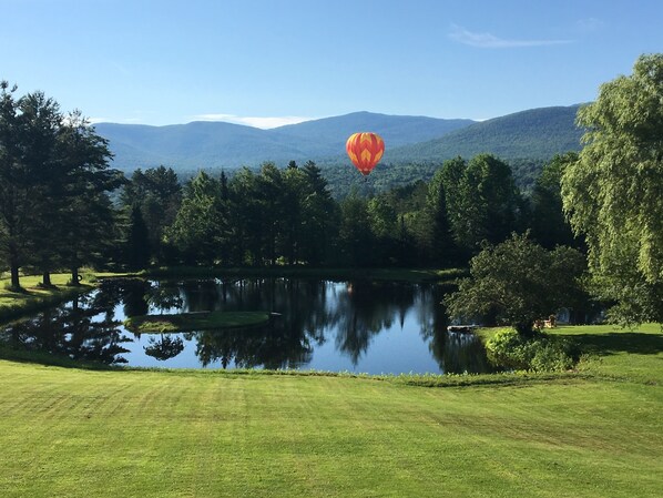 Une montgolfière survolant un lac, avec des montagnes en arrière-plan.