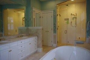 Ein Badezimmer mit einer großen Badewanne, einem Doppelwaschtisch und einer begehbaren Dusche.