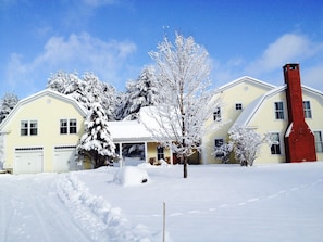 Ein zweigeschossiges Haus mit verschneitem Vorgarten, Schornstein und Garage.