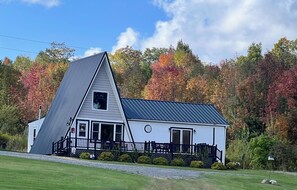 Une maison blanche avec un toit à forte pente et un petit porche.