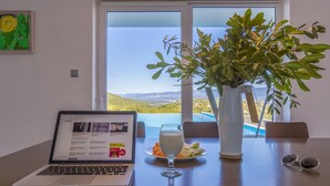 Ein Laptop auf einem Tisch mit einem Glas Milch, einem Teller Essen und einer Topfpflanze.