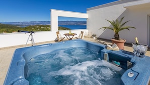 Ein Whirlpool mit freiem Blick auf das Meer und die Berge, ein Stativ und ein Blumentopf.