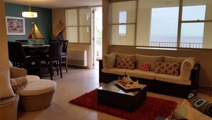A living room with a sofa, chairs, a dining table, and a red rug. - Beautiful Mediterranean Style Ocean View Villa, Spectacular Sunsets!  (Aguadilla)