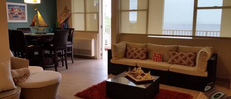 A living room with a sofa, chairs, a dining table, and a red rug.
