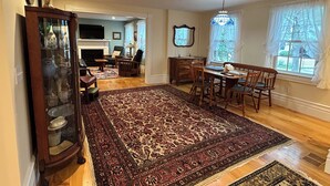 A spacious living room with a large rug, wooden furniture, and a fireplace.