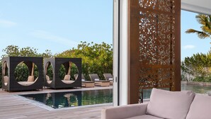 A modern outdoor seating area with a pool, a large window, and a decorative screen.