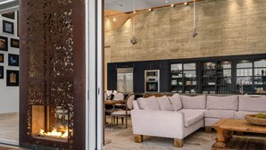 A modern living room with a fireplace, a large sectional sofa, and a dining area with a table and chairs.