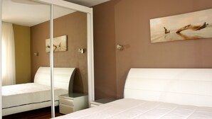 Ein Schlafzimmer mit Bett, Nachttisch, Spiegel und einem Bild an der Wand.