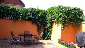 Eine Terrasse im Freien mit Tisch und Stühlen, umgeben von einem Backsteinboden und einer Backsteinmauer.