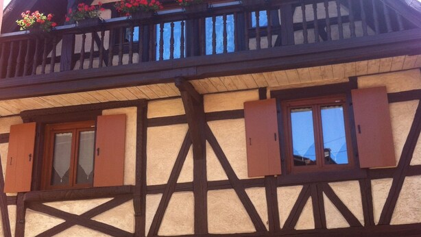 Een klassiek gebouw met vakwerk, een balkon en bloembakken.