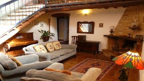 A cozy living room with a staircase, a fireplace, and a large window.