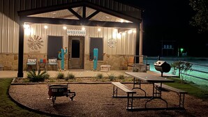 A well-lit building with a 'WELCOME' sign, outdoor seating, and a pool area. - Custom Barndominium Perfect For Romantic Getaways, Lake or Family Vacations (Caldwell)