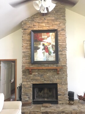 A stone fireplace with a framed abstract painting above it.