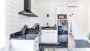 A modern kitchen with white cabinetry, a black stove, and a stainless steel refrigerator. - Modern Farmhouse Style, 1 Block from Forsyth Park by Lucky Savannah (Savannah)
