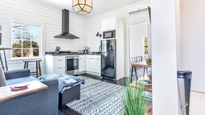 A modern kitchen with white cabinetry, a stainless steel refrigerator, and a black range hood. - Modern Farmhouse Style, 1 Block from Forsyth Park by Lucky Savannah (Savannah)