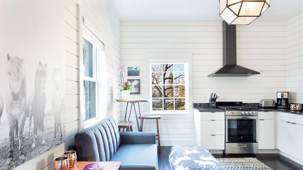 A modern kitchen with white cabinetry, a black stove, and a window with a view of trees. - Modern Farmhouse Style, 1 Block from Forsyth Park by Lucky Savannah (Savannah)
