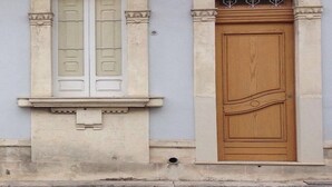 Eine Gebäudefassade mit einer großen Holztür und einem Fenster mit Rollläden.