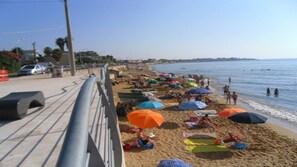 A beach with people sunbathing and swimming, umbrellas, and a metal railing along the shore. - Il Gelsomino, Apartment in Avola (Avola (Siracusa))