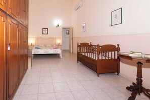 Un dormitori amb llit, bressol de fusta, escriptori i armari.