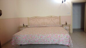 Ein Einzelbett mit floralem Überwurf, zwei Nachttische und eine wandmontierte Leuchte.
