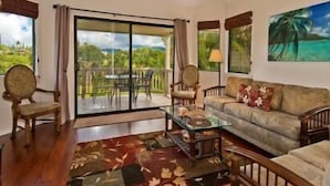 A living room with a sofa, chairs, a coffee table, and a view of a lush landscape through large windows. -  Villa  in Paradise !Mountain Views, Ocean and golf course just  steps away (Princeville)