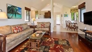A spacious living room with a sofa, coffee table, and a television. There is a dining area with chairs and a table. -  Villa  in Paradise !Mountain Views, Ocean and golf course just  steps away (Princeville)