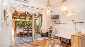 A cozy room with wicker furniture, a television, and a wooden cabinet. - Sea Shell Cottage by the Sea at Capo Coda Cavallo San Teodoro (Capo Coda Cavallo)