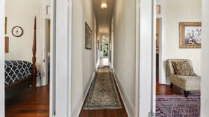 A hallway with a patterned rug, a bed with a patterned bedspread, a chair, and a painting on the wall. - Prime location: Walk to all the French Quarter attractions. Enjoy NOLA with ease (New Orleans)