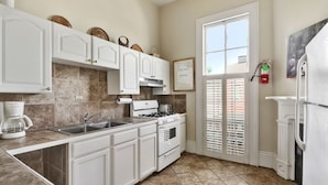 A kitchen with white cabinets, a stove, a sink, and a coffee maker. - Prime location: Walk to all the French Quarter attractions. Enjoy NOLA with ease (New Orleans)