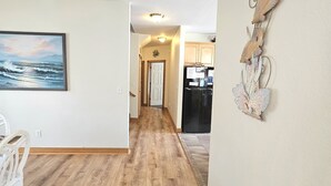 A hallway with wooden flooring, a white wall with a framed picture, and a decorative wall piece. - Beautiful Secluded Canalfront Home. Access to Private Beaches and Marina (Kitty Hawk)