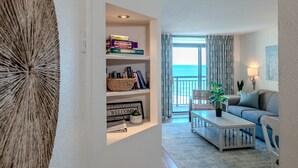 Una sala de estar moderna con una estantería, un sofá, una mesa de centro y vista al mar.