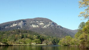 Ein See mit einem Berg im Hintergrund und Bäumen am Ufer.