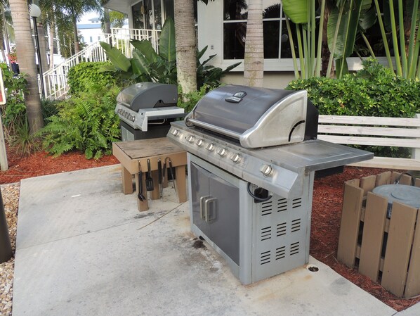Un espace cuisine extérieur comprenant un barbecue, une petite table et un meuble de rangement.