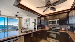 Una cocina moderna con armarios de madera oscura, electrodomésticos de acero inoxidable y una isla grande con fregadero.