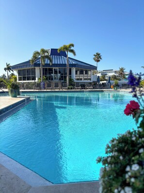 Une piscine avec des chaises longues et, en arrière-plan, un bâtiment doté de grandes fenêtres.