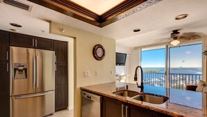 Una cocina con un refrigerador de acero inoxidable, un lavavajillas integrado y un amplio ventanal con vistas a la ciudad.