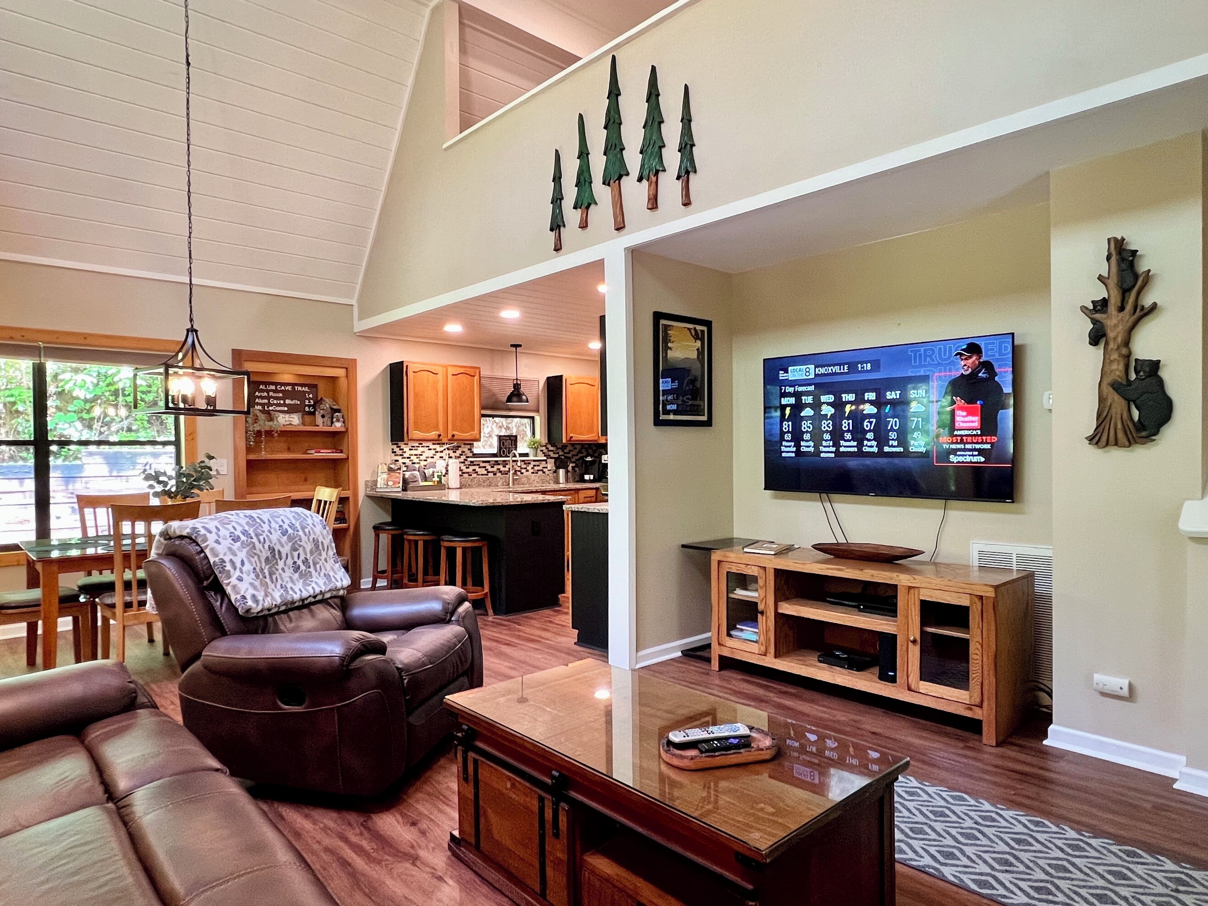 Een moderne woonkamer met een leren bank, een houten salontafel en een flatscreen televisie aan de muur.