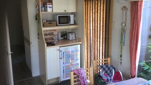 A compact kitchen with a microwave, refrigerator, and a small dining area with chairs. - Mobile home Cadzand-Bad / Retranchement (Retranchement)