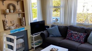 A living room with a sofa, a coffee table, a TV, and a fireplace. - Mobile home Cadzand-Bad / Retranchement (Retranchement)