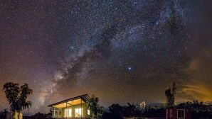 A house with a large open porch under a starry night sky. - Starlit Skies, 1.5 miles to Black Sand Beach, Pet Friendly, Lava Fields, Private (Pahoa)