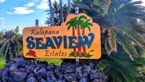 A sign for Kalapana SeaView Estates with palm trees and a clear sky in the background. - Starlit Skies, 1.5 miles to Black Sand Beach, Pet Friendly, Lava Fields, Private (Pahoa)