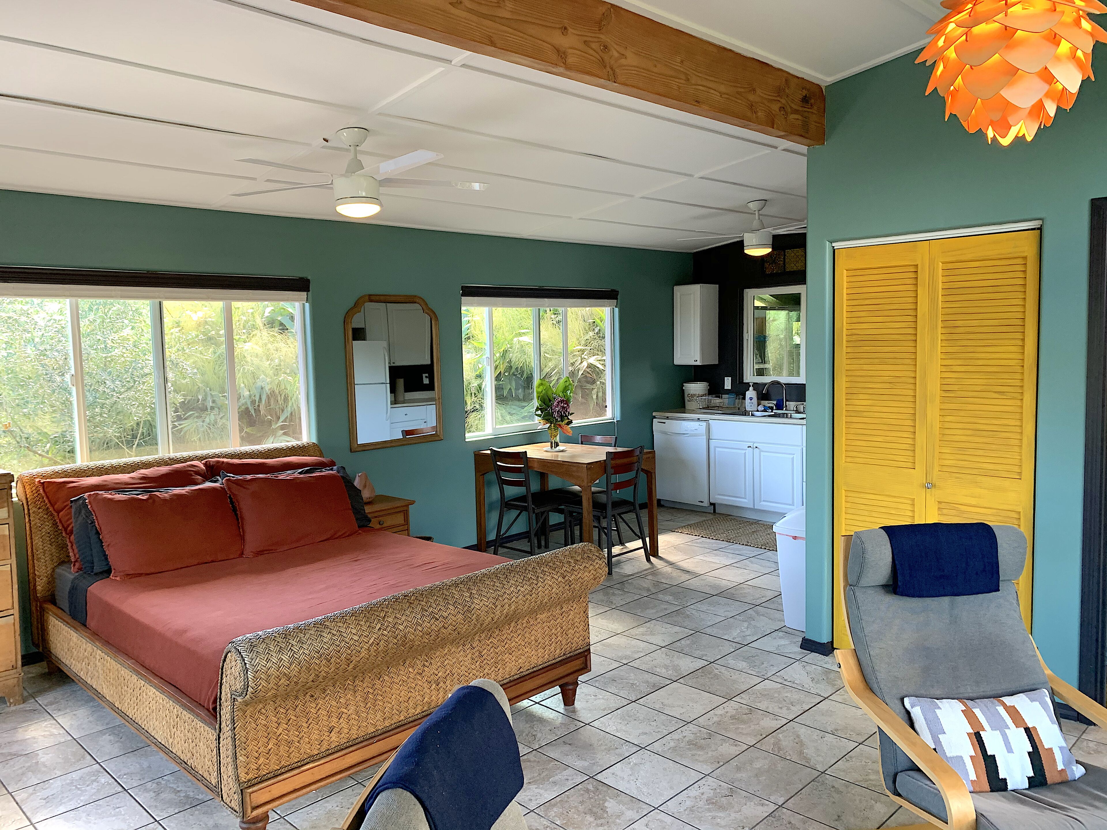 A room with a bed, a dining table, chairs, a kitchen area, and a bathroom.