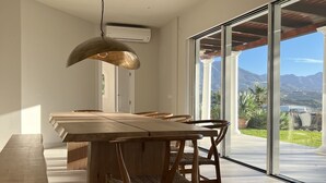 A modern kitchen with a large island, wooden chairs, and a pendant light.