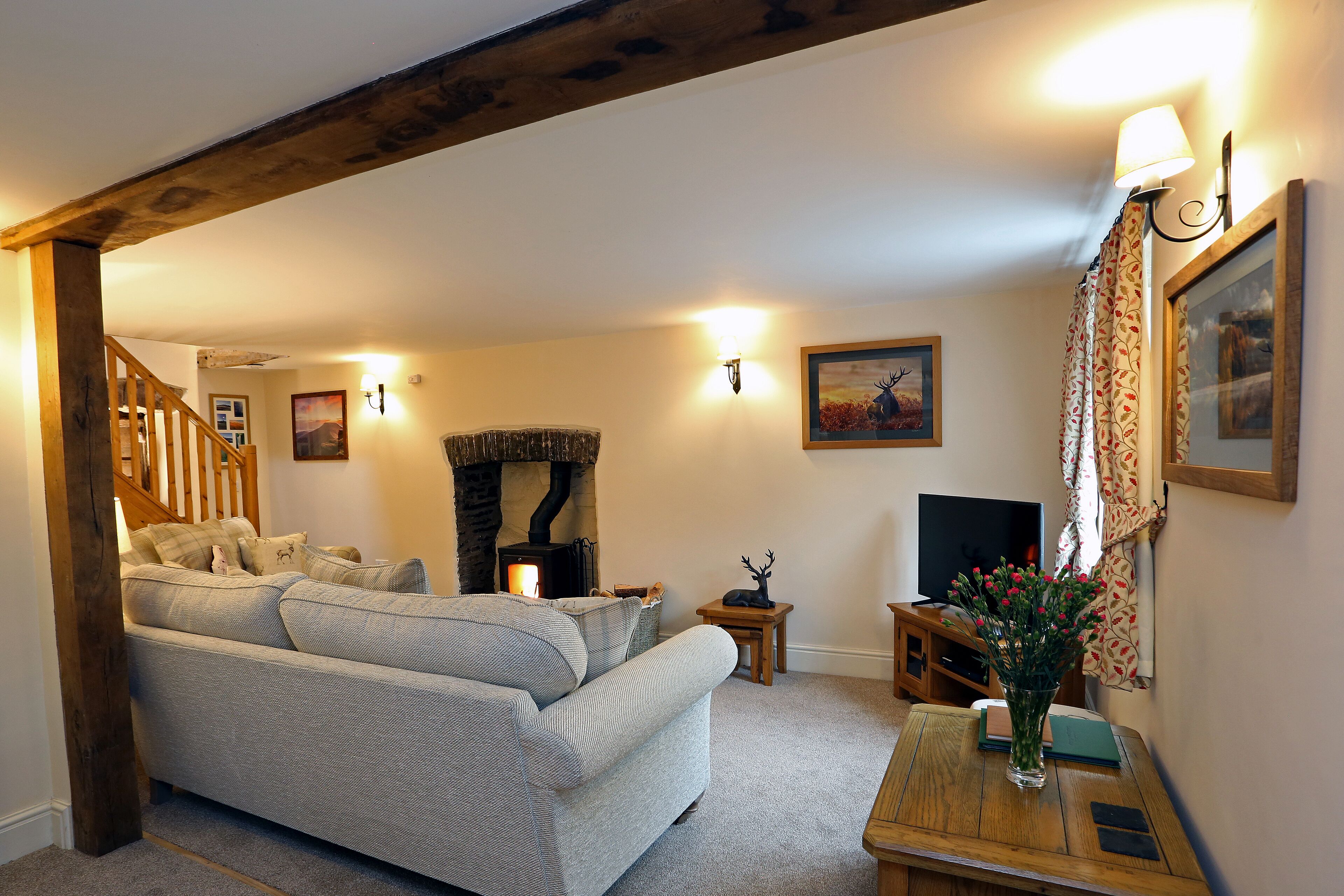 A cozy living room with a sofa, a fireplace, a television, and a staircase.