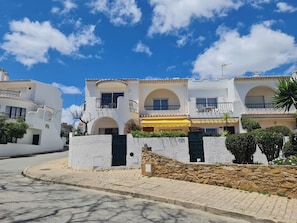 Stylish building with a welcoming entrance, featuring multiple balconies and a stone wall.
