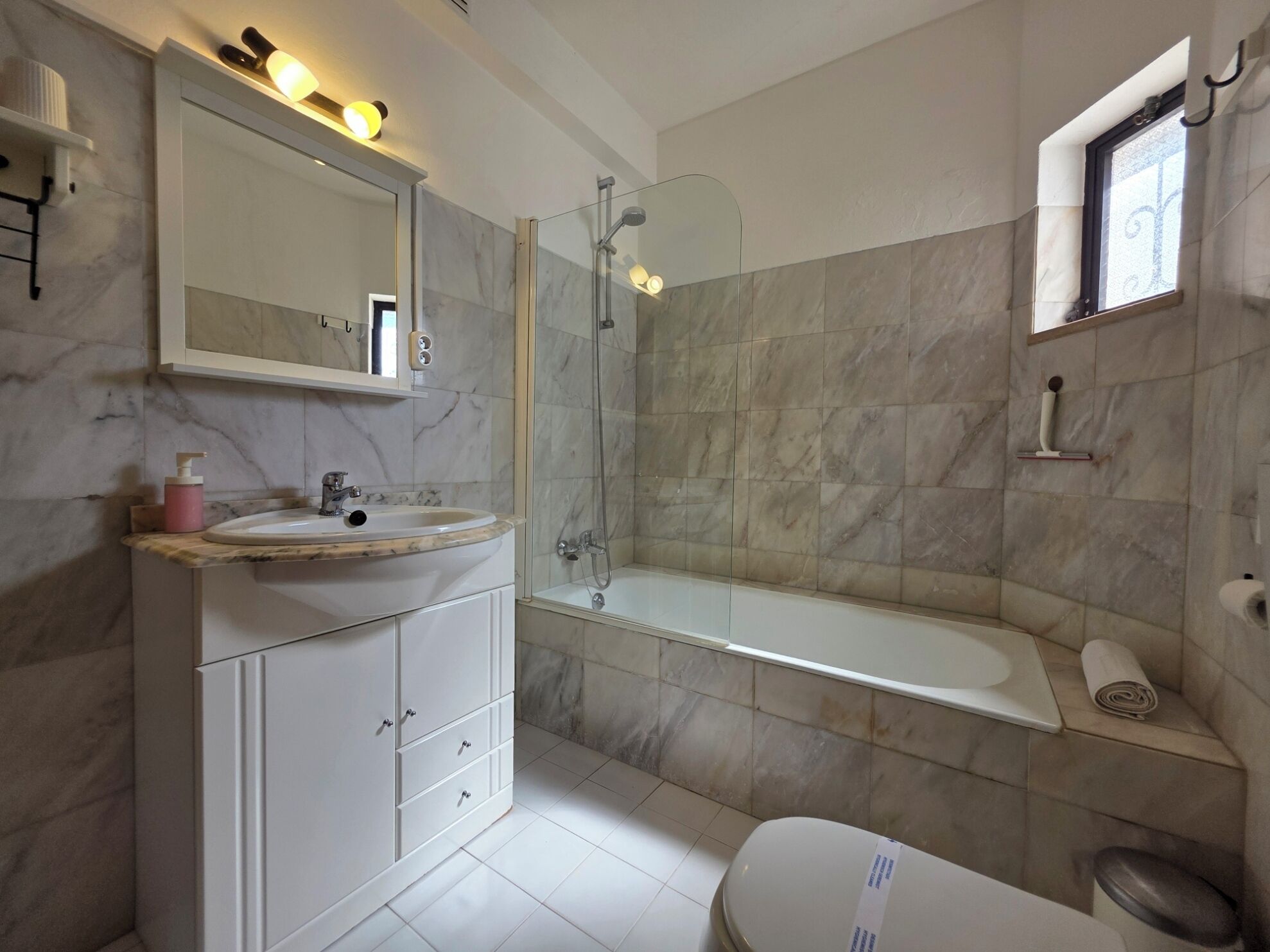 Une salle de bain dotée d’un meuble-lavabo en marbre, d’une douche à parois de verre et de toilettes intégrées.