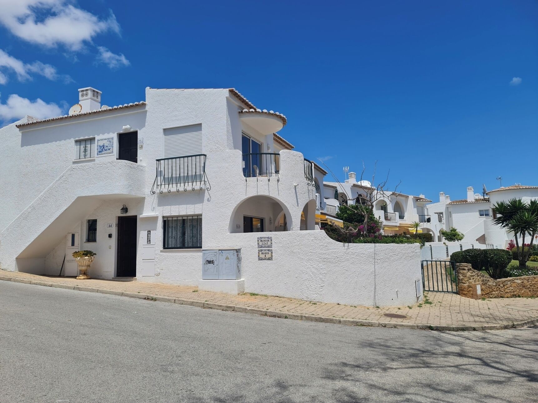 A white building with a balcony, a door, and a sign indicating 'BLOCO 131'.