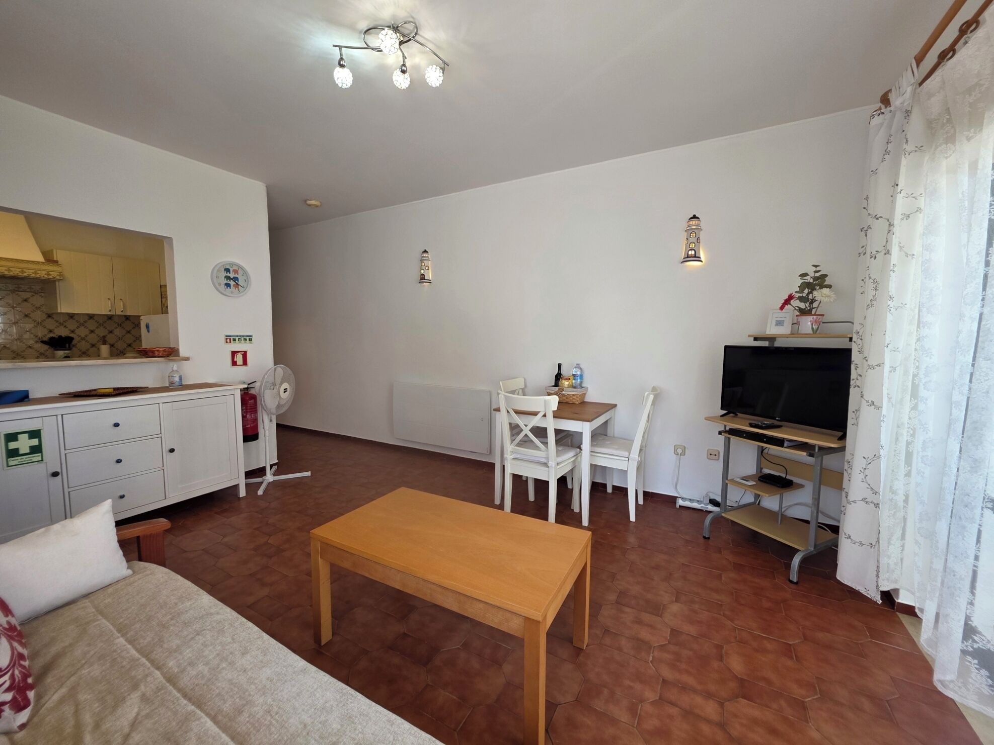 A compact living space with a kitchenette, a dining area, a TV, and a sofa.