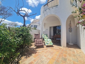Relax on the patio with a comfortable lounge chair and dining area amidst lush greenery.