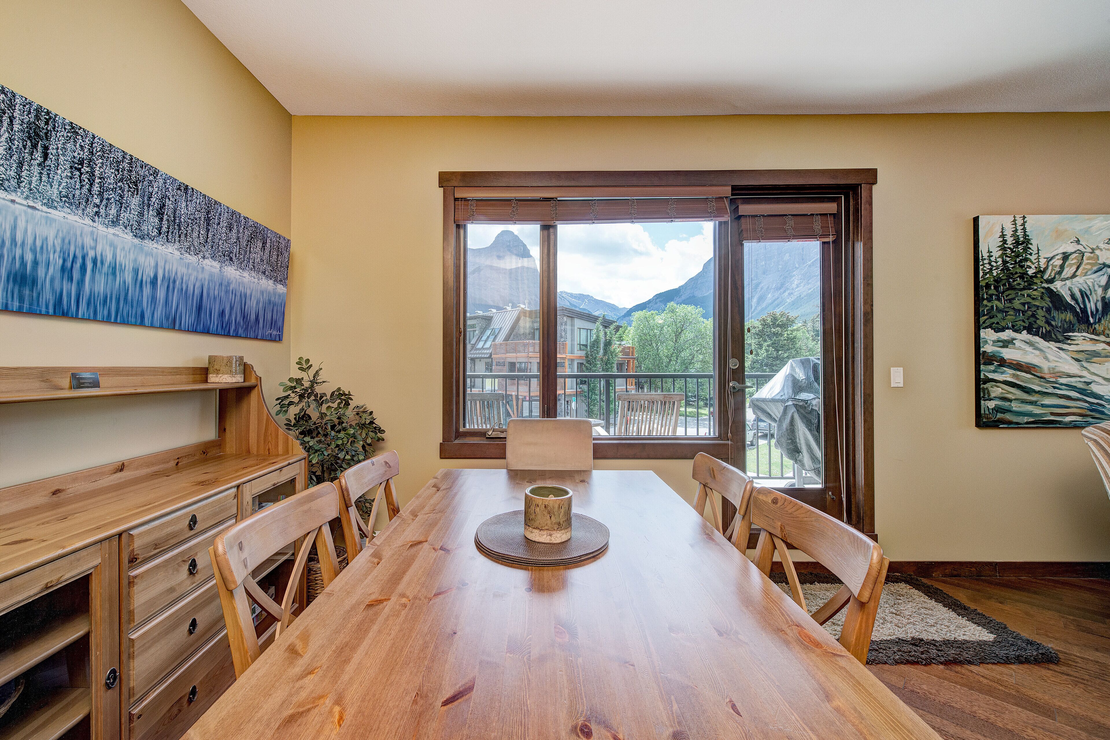 Un comedor con una mesa de madera, sillas y vistas a las montañas a través de un ventanal grande.